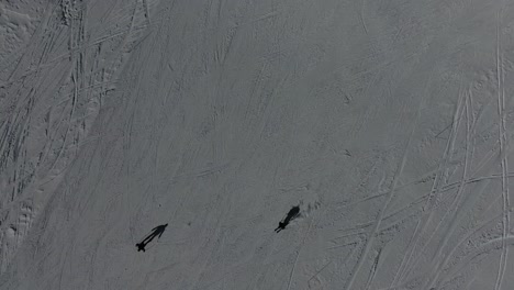 Drone-shot-of-skiers-riding-down-a-mountain-in-the-French-Alps.-Sunny-day